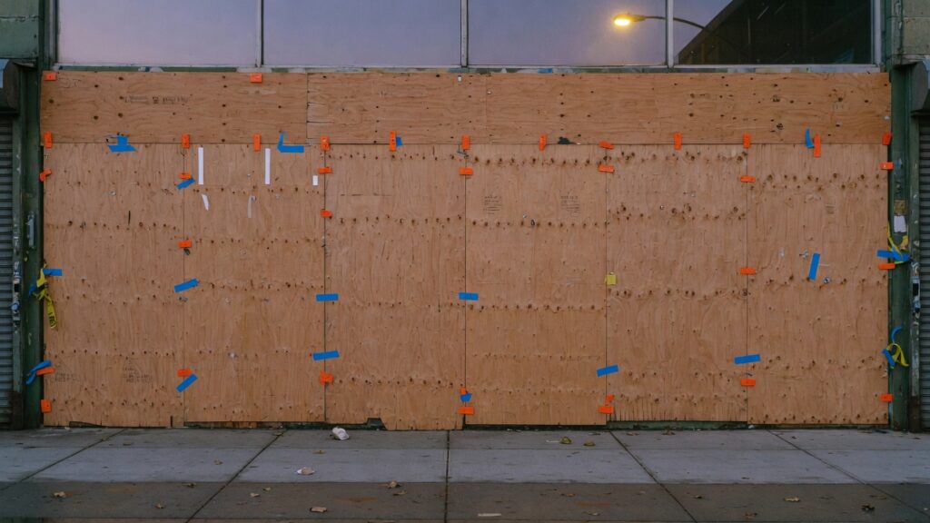 Plywood weather protection on a commercial storefront at dusk