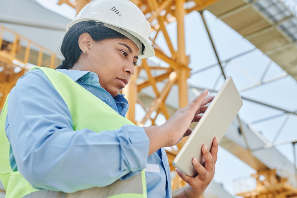 Field worker in hard hat using a tablet at a construction site