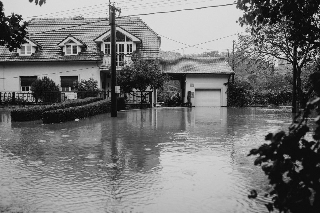 Black and white photo of a suburban house surrounded by floodwater