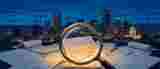 Denver skyline at dusk with construction cranes; a magnifying glass over insurance acquisition documents