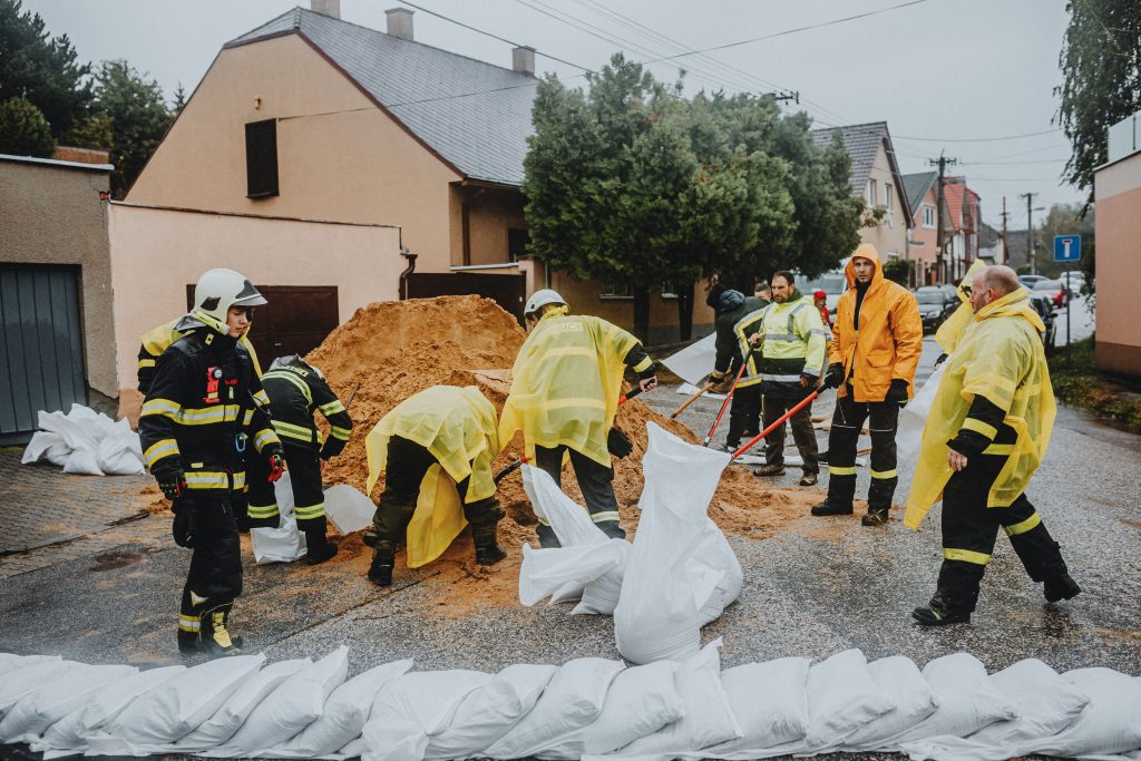 Emergency response workers filling sandbags during a flood, representing the hands-on bottleneck in restoration work