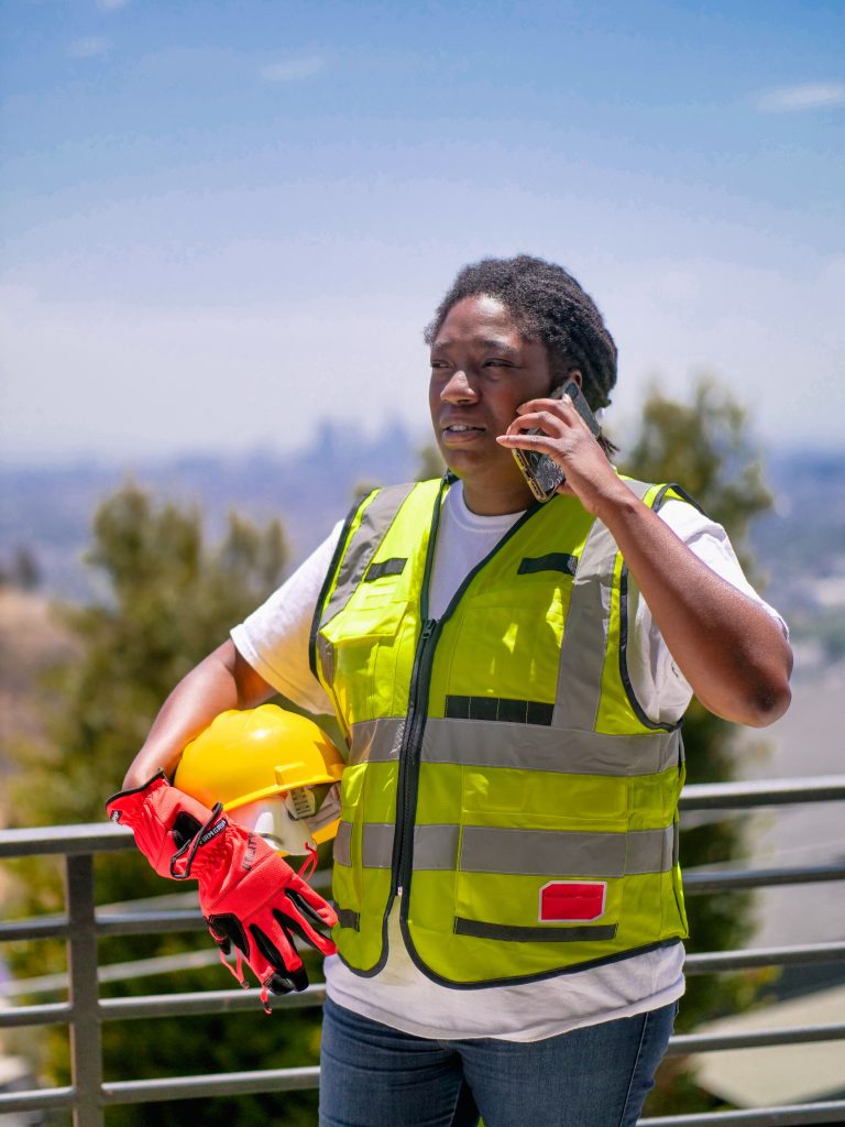 Construction worker in reflective vest talking on a phone outdoors