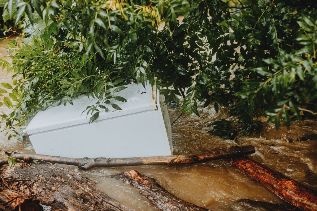 Washing machine swept away by floodwaters, showing the chaos of a water damage event